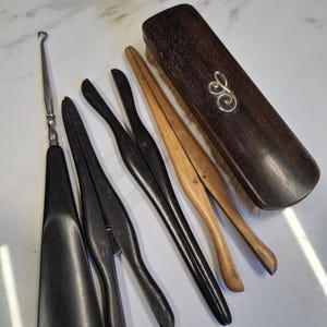 Può includere: Un set di strumenti vintage per la cura delle scarpe, tra cui un calzascarpe, due forme per scarpe, un paio di stira-scarpe e una spazzola per scarpe in legno con un monogramma d'argento.