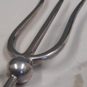 May include: A silver three-pronged fork with a round handle.