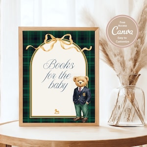 May include: Wooden framed sign with a green and black plaid background. The sign has a gold bow and the text "Books for the baby". A teddy bear in a blazer and slacks is on the sign. A vase with dried flowers is on the table.