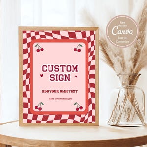 May include: A framed custom sign with a pink background and a red checkered border. The sign reads "CUSTOM SIGN" with the text "ADD YOUR OWN TEXT" below. Cherries decorate the corners. A Canva logo is in the upper right corner.