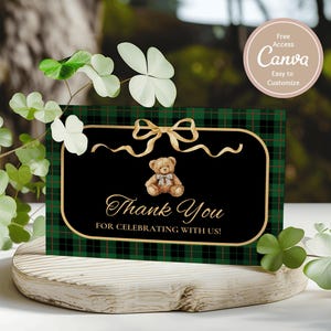 May include: A thank you card with a black background and gold trim, featuring a teddy bear illustration and the words "Thank You For Celebrating With Us!". The card has a green and black plaid pattern.