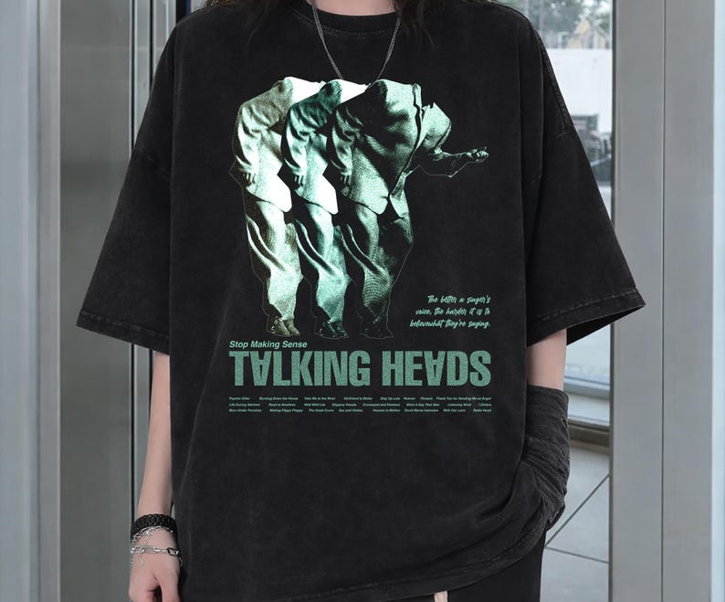 May include: Black oversized t-shirt featuring a graphic of three figures in suits with the text "TALKING HEADS" in green. The shirt also includes the text "Stop Making Sense" and other text below the band's name.