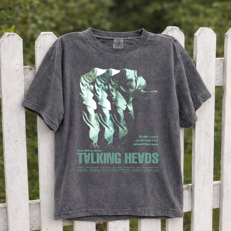 May include: Dark gray t-shirt featuring a green graphic of three figures in suits, with the text "Stop Making Sense" above "TALKING HEADS" in green. The shirt has a vintage, worn look.