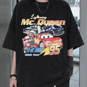 Puede incluir: Camiseta negra con un dise&ntilde;o de Rayo McQueen de la pel&iacute;cula Cars, con el texto "Lightning McQueen" y "95". El dise&ntilde;o incluye otros personajes de Cars y la frase "think fast".