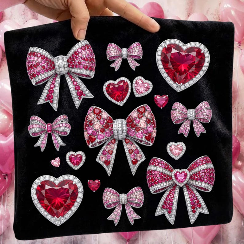 Puede incluir: Un coj&iacute;n negro adornado con varios dise&ntilde;os de lazo y coraz&oacute;n enjoyados. Los lazos y corazones son en tonos de rosa y rojo, con acentos plateados. Las gemas est&aacute;n dispuestas para crear un efecto brillante, perfecto para un tema rom&aacute;ntico.