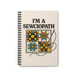 May include: Spiral-bound notebook with the text "I'M A SEWCIOPATH" in black. The notebook cover features a colorful patchwork design with a needle and thread illustration. The design includes squares, stars, and floral patterns in shades of green, yellow, and orange.