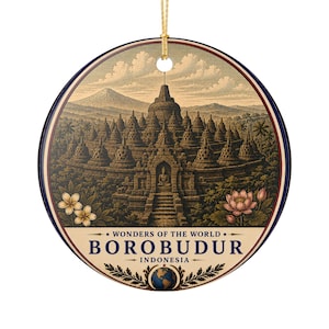 Könnte beinhalten: Ein rundes Keramikornament mit einer detaillierten Illustration des Borobudur-Tempels in Indonesien, einem Berg im Hintergrund, Lotusblumen und dem Text WONDERS OF THE WORLD BOROBUDUR INDONESIA, aufgehängt an einer goldenen Schnur.