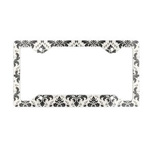 May include: A license plate frame with a white background and a black damask pattern. The frame has a rectangular shape with cutouts for mounting. The damask design features floral and scroll elements.