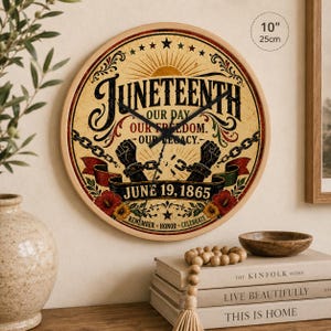 Puede incluir: Un reloj redondo de madera con una esfera color crema con el texto "Juneteenth" y la fecha 19 de junio de 1865. La esfera del reloj incluye ilustraciones de cadenas, puños y flores. El reloj tiene 25 cm de diámetro.