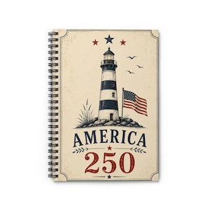 Op de afbeelding: Een spiraalgebonden notitieboek met een crèmekleurige kaft met een zwart-witte illustratie van een vuurtoren, een wapperende Amerikaanse vlag, drie sterren en de tekst AMERICA 250 in blauwe en rode letters met decoratieve krullen.