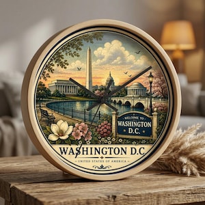 May include: A round wall clock with a light wood frame featuring a printed illustration of the Washington D.C. skyline, including the Washington Monument and Capitol building. The text reads Welcome to Washington D.C. and Washington D.C. United States of America.