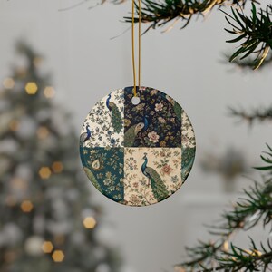 Może przedstawiać: Okrągła ceramiczna ozdoba z patchworkowym wzorem składającym się z czterech oddzielnych paneli. Każdy panel przedstawia szczegółowy motyw pawia otoczony misternymi wzorami kwiatowymi w odcieniach granatu, kremu, turkusu i zieleni, zawieszona na złotym sznurku.