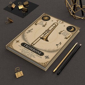 Könnte beinhalten: Ein beigefarbenes Notizbuch mit einer zentralen Posaunen-Illustration, Sonnen- und Mondsymbolen sowie dem Text TROMBONE, MOVE THE AIR, MOVE HEARTS und BIG SOUND, BOLD SOUL, PURE IMPACT. Der Einband zeigt zudem Noten und Sterne.