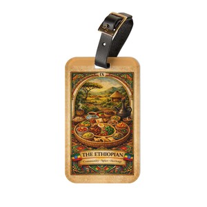 May include: Luggage tag with a black leather strap and gold-colored buckle. The tag features a detailed illustration of an Ethiopian meal, with the text "THE ETHIOPIAN" and the words "Community, Spice, Heritage".