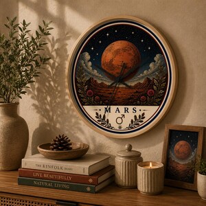 Peut inclure: Une horloge murale ronde avec un cadre en bois clair présentant une illustration céleste de la planète Mars, un ciel étoilé et un paysage rocheux. Le cadran affiche le texte MARS avec le symbole masculin et des accents botaniques.