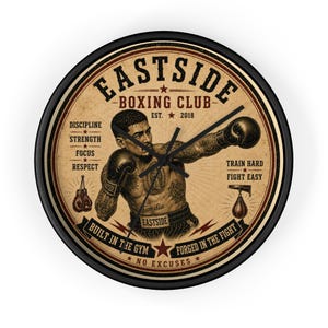 Puede incluir: Reloj de pared redondo con marco negro. La esfera tiene un diseño vintage con una ilustración de boxeador y el texto "Eastside Boxing Club". Incluye las palabras "Disciplina, Fuerza, Enfoque, Respeto".