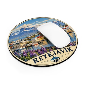 Peut inclure: Un tapis de souris rond illustrant le port de Reykjavik avec des fleurs de lupin violettes au premier plan, des montagnes enneigées en arrière-plan et le texte REYKJAVIK imprimé en lettres bleu foncé avec une icône de montagne.