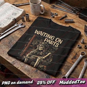 Puede incluir: Camiseta negra con el texto "WAITING ON PARTS" y una ilustración de un esqueleto con casco y llave inglesa. La imagen incluye herramientas y un catálogo de piezas sobre una superficie de madera.