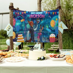 Op de afbeelding: Een verjaardagsbanner met de tekst "HAPPY BIRTHDAY JACKSON" en stripfiguren. Een taart met een auto erop en andere desserts staan op een tafel. Kleurrijke ballonnen en decoraties zijn zichtbaar.