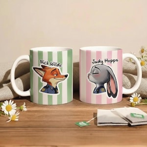 Peut inclure: Deux mugs en c&eacute;ramique blanche avec des illustrations de personnages. L'un pr&eacute;sente Nick Wilde, un renard, sur un fond &agrave; rayures vertes. L'autre pr&eacute;sente Judy Hopps, un lapin, sur un fond &agrave; rayures roses. Les deux mugs ont des anses blanches et les noms des personnages.