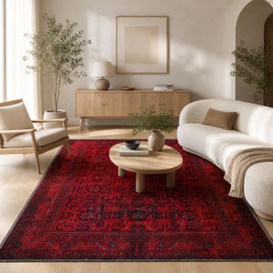 May include: A vibrant red rug with an intricate geometric design is the focal point of the room. The rug's rich red hue is contrasted by black detailing. The rug is in a living room, with a wooden coffee table and a curved white sofa. The rug measures approximately 240 x 300 cm.
