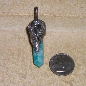 May include: A silver lion head pendant with a green aventurine stone. The pendant is about the size of a US dime.
