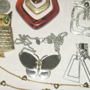 May include: A collection of vintage jewellery featuring a gold owl brooch, a gold butterfly pendant necklace, a silver geometric brooch, and silver dangle earrings.