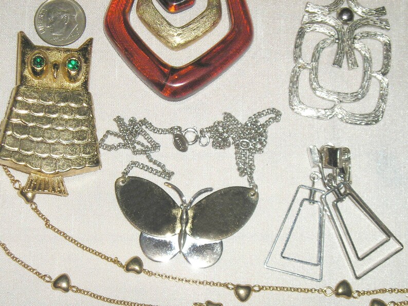 May include: A collection of vintage jewellery featuring a gold owl brooch, a gold butterfly pendant necklace, a silver geometric brooch, and silver dangle earrings.