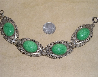 May include: A silver bracelet with four green oval cabochon stones set in filigree designs. The bracelet has a clasp closure.