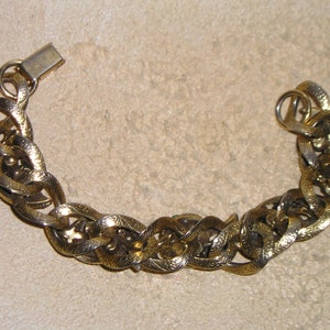 May include: A gold chain bracelet with a textured design. The bracelet has a clasp closure.