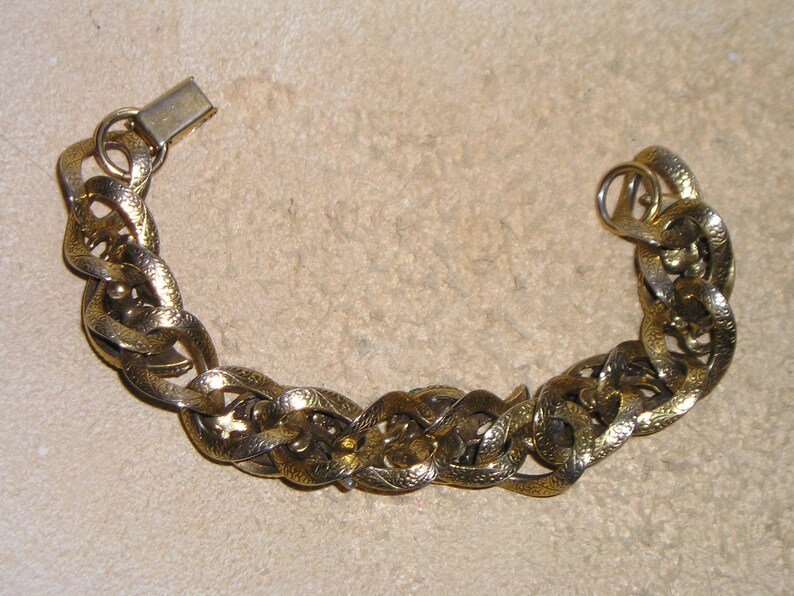 May include: A gold chain bracelet with a textured design. The bracelet has a clasp closure.