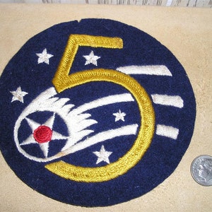 May include: A blue felt patch with a gold number "5" and a white wing with a red center star. There are white stars around the number and wing.