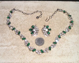 May include: A vintage jewelry set featuring a necklace and matching earrings. The necklace and earrings are silver-toned and adorned with clear and emerald-green rhinestones. A dime is included for size reference.