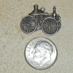 May include: Silver charm of a vintage steam engine, about the size of a US dime.