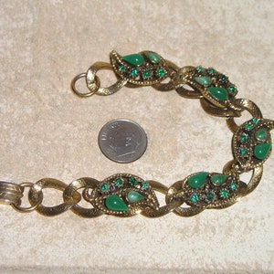 May include: A gold tone bracelet with a chain link design. The bracelet is decorated with green teardrop-shaped stones and smaller green rhinestones.