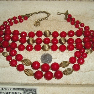 Puede incluir: Un collar de cuatro hileras de cuentas rojas y doradas con un cierre. El collar está hecho de cuentas rojas grandes y facetadas y cuentas doradas más pequeñas. El collar mide aproximadamente 46 cm de largo.