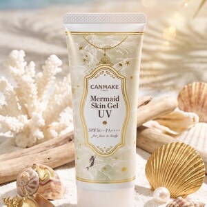 May include: A tube of CANMAKE Mermaid Skin Gel UV SPF50+ PA++++ for face & body. The tube is white with gold detailing and a mermaid illustration. The image is set on a sandy beach with seashells, pearls, and driftwood.