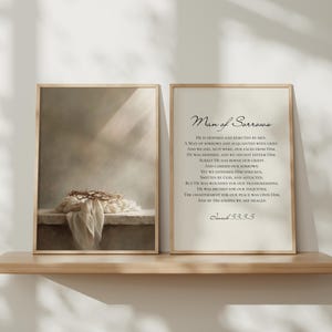 May include: Two framed prints on a wooden shelf. The left print shows a crown of thorns and draped cloth. The right print has the text "Man of Sorrows" and a Bible verse. Both prints are in wooden frames.