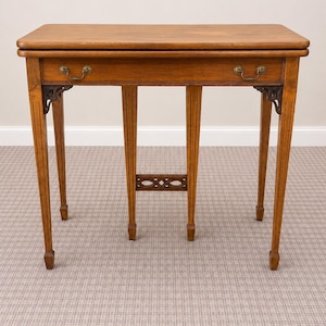 May include: A wooden side table with a rectangular top and two drawers. The table has four slender legs, each with vertical grooves, and decorative metal corner brackets. The table is approximately 76 cm long.