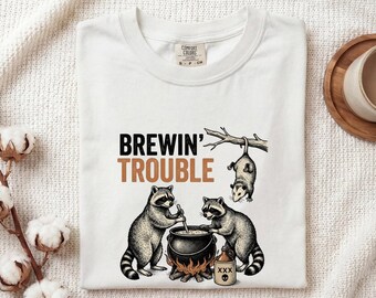 Maglietta con calderone e procione, regalo di Halloween a tema animali, maglietta vintage da donna, maglietta con calderone da strega, maglietta horror per fan, maglietta retrò, grafica di creature disegnata a mano