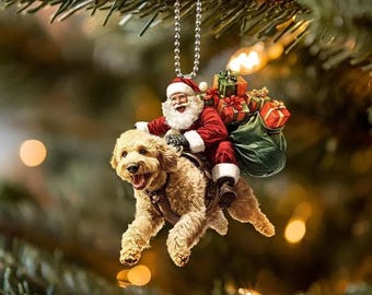 May include: A Christmas ornament featuring Santa Claus riding a golden doodle dog. Santa is dressed in a red suit and hat, carrying a sack of gifts. The dog has a harness and is mid-stride, with a happy expression.
