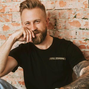 Pode incluir: Uma placa de madeira rústica com o texto "Welcome to our home" em letras brancas. A placa apresenta um acabamento desgastado e um design simples e convidativo.