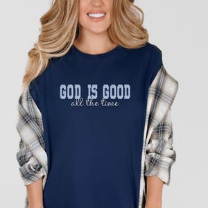 Women’s navy Christian t-shirt “God is good all the time” layered with plaid shirt, casual fall outfit, inspirational faith apparel everyday wear