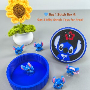 K&ouml;nnte beinhalten: Ein blauer Beh&auml;lter mit Stitch-Figuren und einem Stitch-Deckel. Eine geh&auml;kelte Sonnenblume in einem wei&szlig;en Topf ist ebenfalls vorhanden. Der Text lautet: Kaufe 1 Stitch Box & erhalte 3 Mini Stitch Spielzeuge gratis!