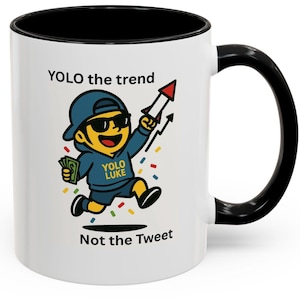 May include: White ceramic mug with a black interior and handle. The mug features a cartoon illustration of a character wearing sunglasses and a blue hoodie, holding a rocket and money. Text on the mug reads "YOLO the trend" and "Not the Tweet."