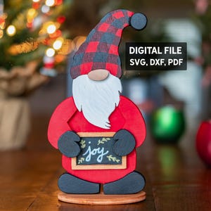 May include: Wooden gnome decoration with a red body, black and red plaid hat, and white beard. The gnome holds a small chalkboard sign that reads "joy". The image also includes text that says "DIGITAL FILE SVG, DXF, PDF".