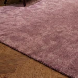 Puede incluir: Una alfombra grande, de color malva, con una superficie suave y texturizada. La alfombra est&aacute; colocada sobre un suelo de madera con un patr&oacute;n de espiga. La alfombra est&aacute; en una habitaci&oacute;n con muebles.