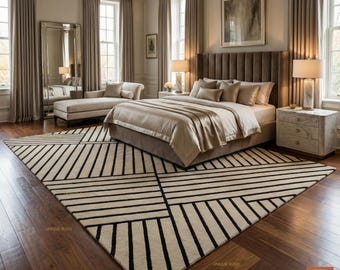 May include: A luxurious bedroom featuring a large bed with a brown headboard, beige bedding, and a geometric black and white rug. The room includes a chaise lounge, curtains, and marble bedside tables.