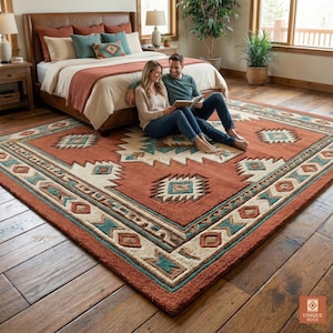 以下が含まれることがあります： 南西部のデザインの大きな長方形のラグ。ラグは、クリーム、ティール、ブラウンの幾何学模様の錆色の背景が特徴です。 ラグは寝室の木製の床に置かれています。