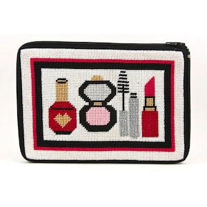 May include: A white canvas zippered pouch with a black zipper and a black border. The pouch has a colorful embroidered design of makeup items, including a red nail polish bottle, a pink blush compact, a black mascara wand, a silver eyeliner pencil, and a red lipstick.